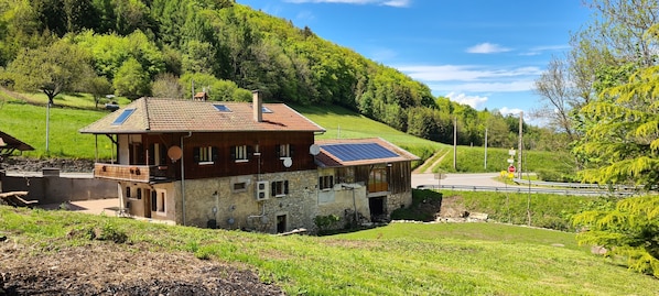 A rustic chalet with a stone facade, a wooden balcony, and solar panels on the roof.