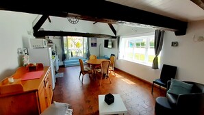 A spacious room with a wooden dining table, chairs, a sofa, and a kitchen area with a washing machine. - "La Beuvrequentoise 2" just a stone's throw from Boulogne sur mer with NAUSICCA, Wissant  (Beuvrequen)