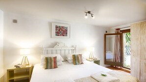A hotel room with a large bed, two bedside tables, a ceiling fan, a window with curtains, and a framed picture on the wall.