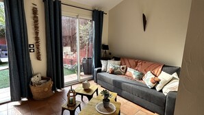 A living room with a sofa, two small tables, a basket, and a sliding glass door to the outside. - Grenache (Collioure)
