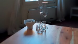 A wooden table with a white bowl and four clear glasses.