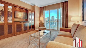 A spacious living room with a large flat-screen TV, a glass coffee table, a sofa, and a city view through floor-to-ceiling windows. - Signature 2Br3Ba F1 View Balcony Ste 30-719 and 21 (Las Vegas)