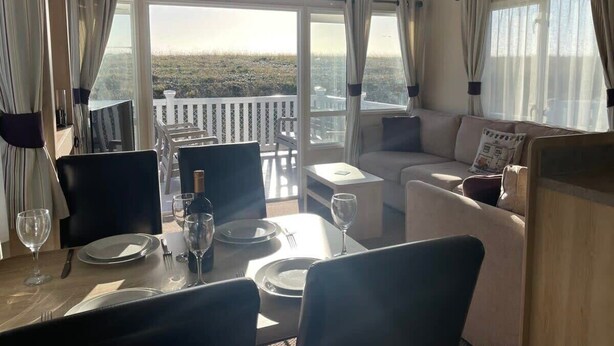 Un comedor con una mesa dispuesta para cuatro personas, un sofá y un balcón con vistas.