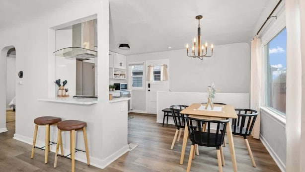 Et moderne køkken med en central ø, barstole og et spiseområde med et bord og stole.