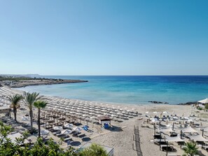 En la playa, playa de arena blanca, camastros y sombrillas 
