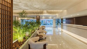 A modern lobby with a reception desk, seating area, and indoor plants. - So White Beach Resort (Ayia Napa)
