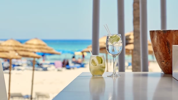 A table with two drinks and a wooden bowl at a beachside location. - So White Beach Resort (Ayia Napa)