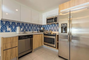 Fully equipped kitchen with stainless steel appliances, refrigerator, microwave, and dishwasher.