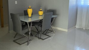 A dining area with a table, chairs, and two yellow vases. - Beautiful apartment in residential in front of the sea (Santo Domingo Este)