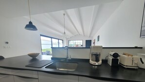 Eine moderne Küche mit schwarzem Arbeitsplatz, einer Spüle, einer Kaffeemaschine und einem Toaster.