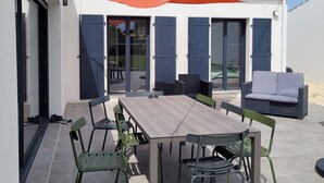 Eine Terrasse mit Holztisch und -stühlen, einer Couch und einer Schaukel.