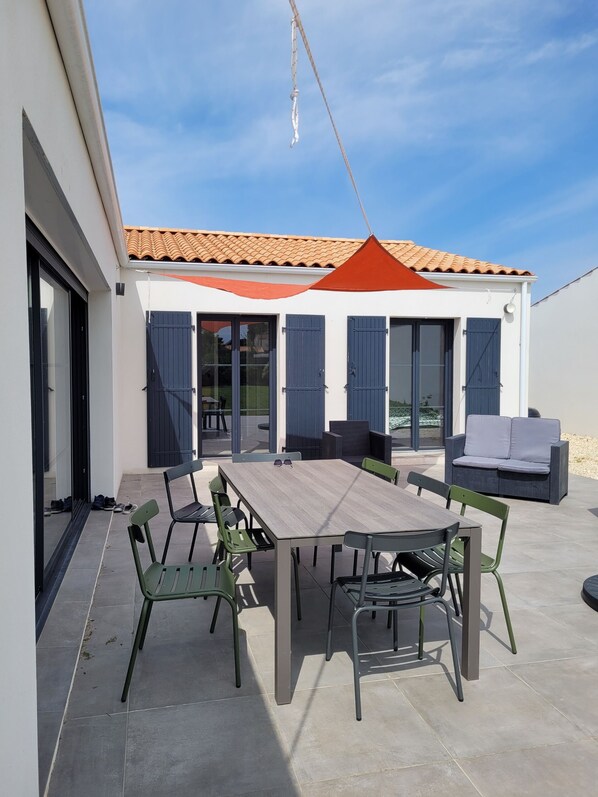 Une terrasse avec une table et des chaises en bois, un canapé et une balançoire.
