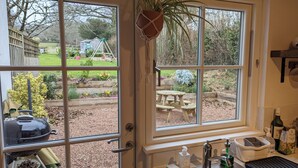 Eine Küche mit einem großen Fenster, einem Spülbecken und einem Grill draußen.