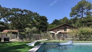Une piscine avec une terrasse en bois et un petit bâtiment en arrière-plan.