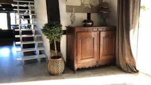 Un meuble en bois avec un dessus décoratif, une petite plante en pot et un tableau représentant des poulets accroché au mur.