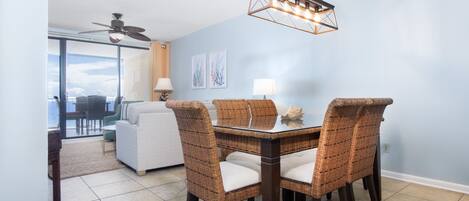 Un comedor con mesa y sillas, un ventilador de techo y vistas al exterior.