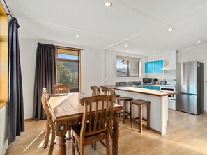 A modern kitchen with a central island, wooden dining table, and chairs.
