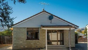 A small, single-story house with a sloped roof, a satellite dish, and a garage door.