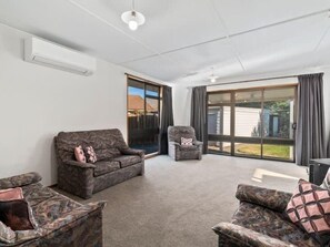 A spacious living room with a large sliding glass door leading to a backyard. There are two sofas and a chair. - Holiday Heaven - Cromwell (Cromwell)