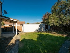 A backyard with a covered patio, a white shed, and a wooden fence. - Holiday Heaven - Cromwell (Cromwell)