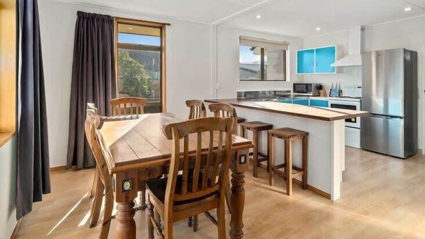 A modern kitchen with a central island, wooden dining table, and chairs.