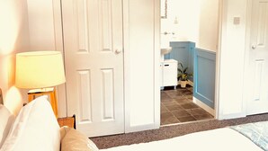 Une chambre d’hôtel avec un lit, une lampe, une salle de bain avec un lavabo et une plante en pot.