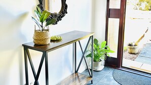 Un couloir avec une console en bois foncé, un grand miroir décoratif et une plante en pot.