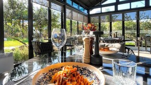 Ein Essbereich mit einem Tisch, gedeckt für zwei Personen, mit Pasta, Gläsern und einer Salzlöffel und Pfefferlöffel.