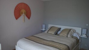 A bedroom with a bed, two bedside tables, and a wall-mounted fan. - Bellevue residence. Bed and breakfast between Pau, Lourdes and Tarbes (Pontacq)