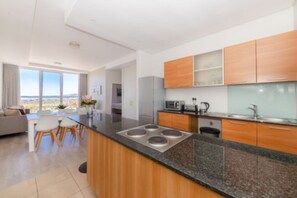 A modern kitchen with a central island, wooden cabinets, and a large window offering a view.