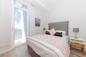 A bedroom with a bed, bedside tables, a window, and a door.
