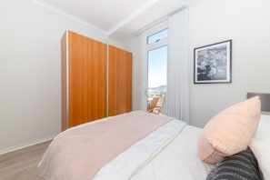 A bedroom with a bed, a window, a wardrobe, and a framed picture on the wall. - Spacious Blouberg Beachfront Pad with Pool access (Cape Town)
