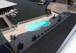A swimming pool with lounge chairs and tables, a dock with boats, and a building with a covered area. - BRAND NEW HARDWOOD FLOORS! Beautiful views, walk to Strip, shopping and fun!  (Lake Ozark)