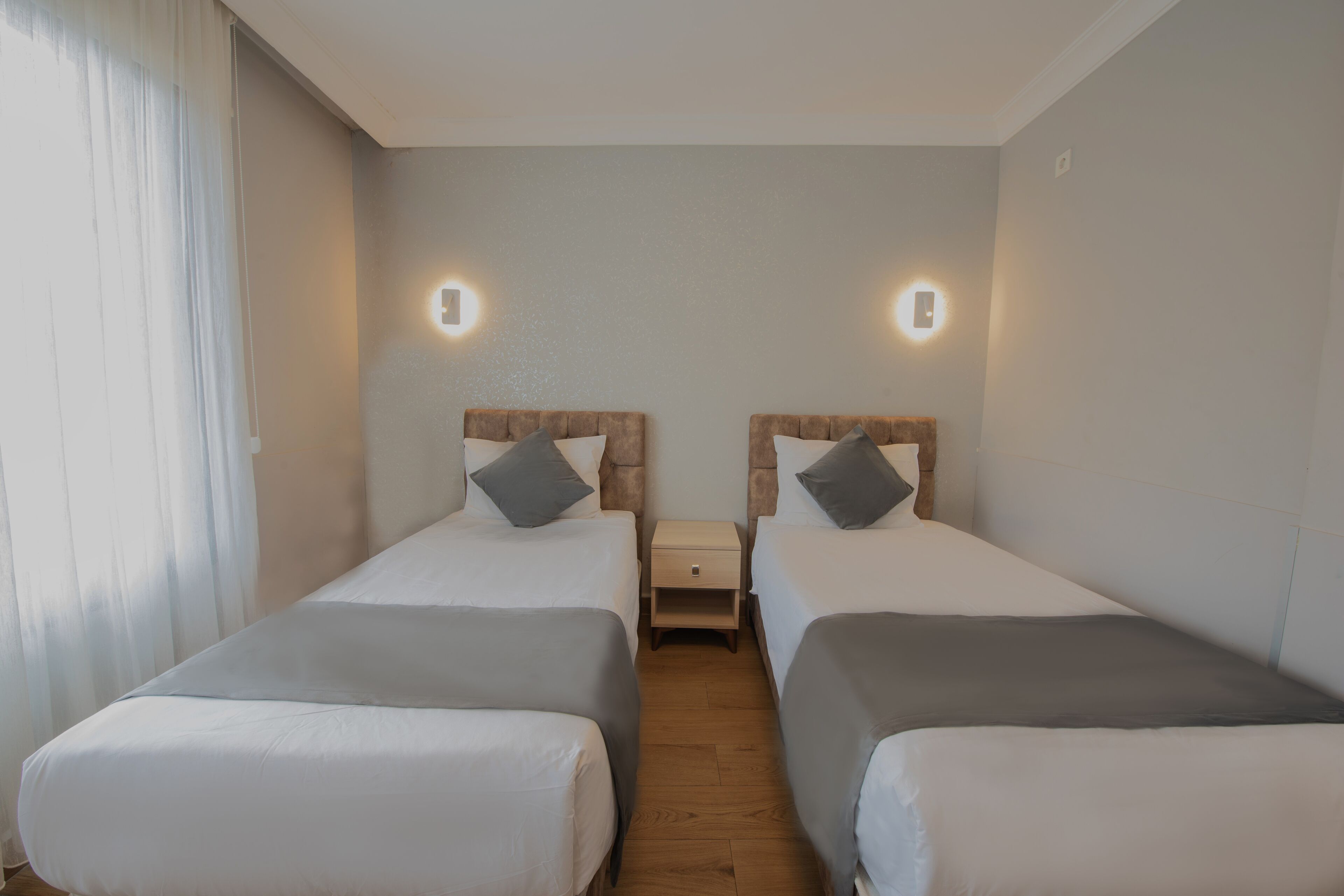Ein Hotelzimmer mit zwei Einzelbetten, einem Nachttisch und Wandleuchten.