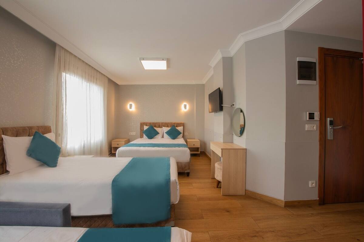 A hotel room with two beds, a desk, a TV, and a door.