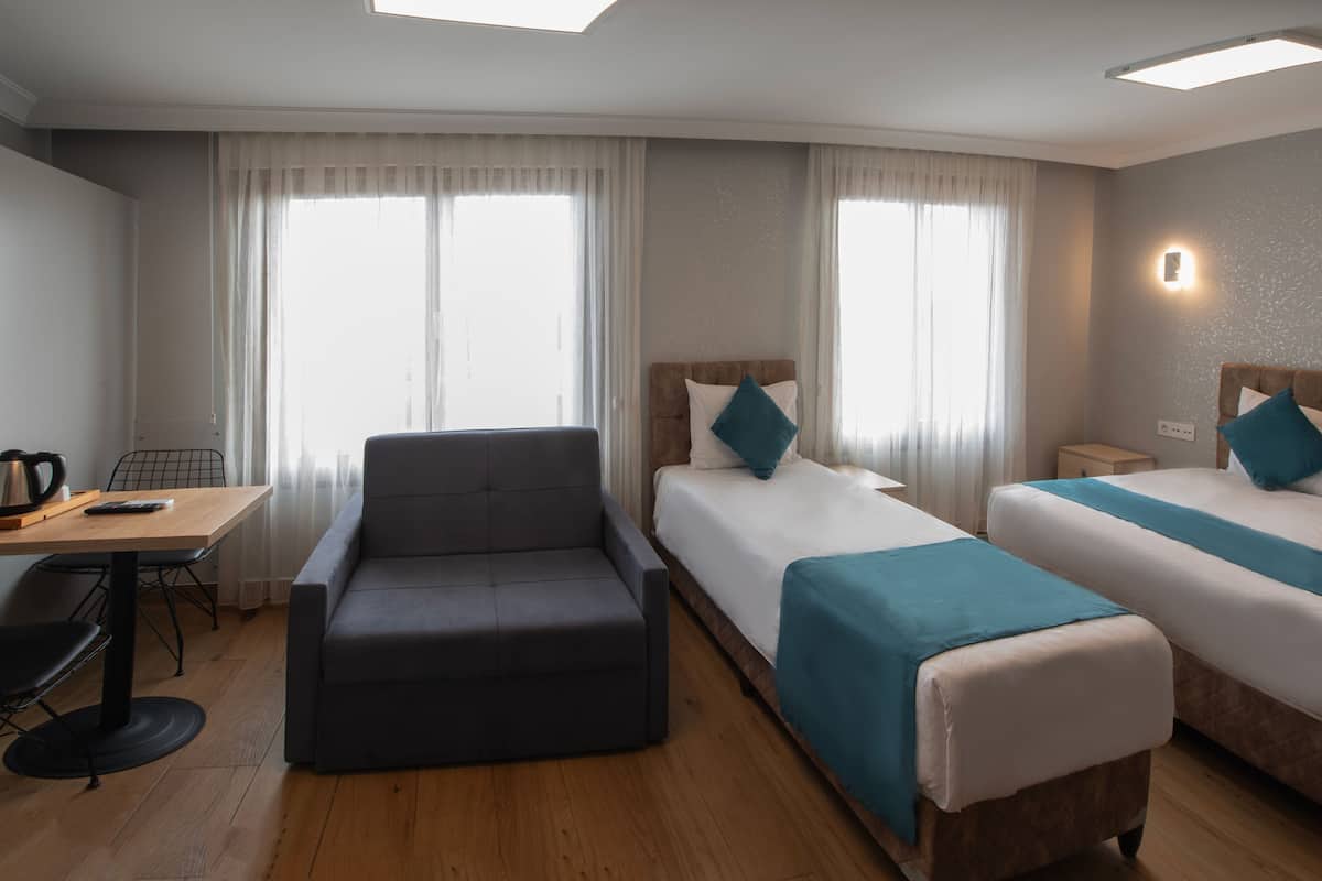A hotel room with two beds, a sofa, a desk, and a chair.
