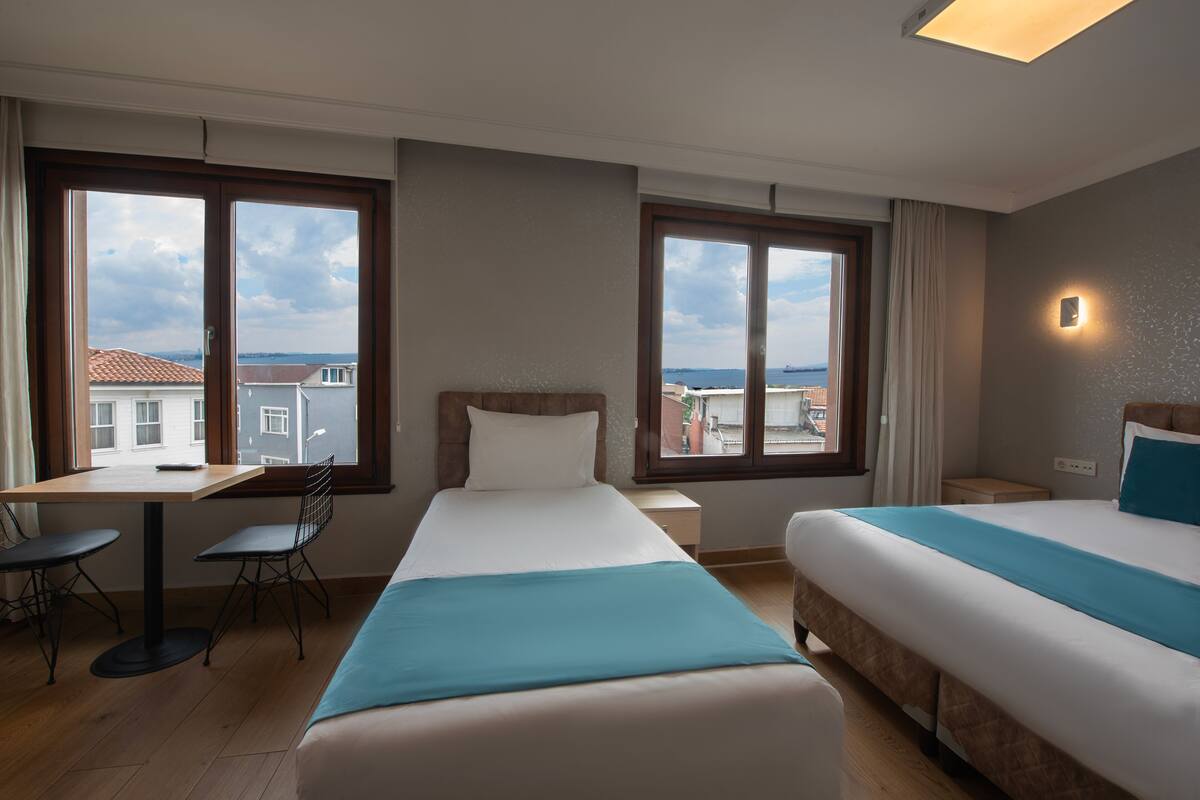A hotel room with two beds, a desk, and chairs.