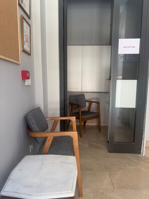 A reception area with a reception desk, two wooden chairs with grey cushions, a corkboard on the wall, and a sign indicating 'RECEPTION'. - SEVEN STUDIOS SULTANAHMET (Istanbul)