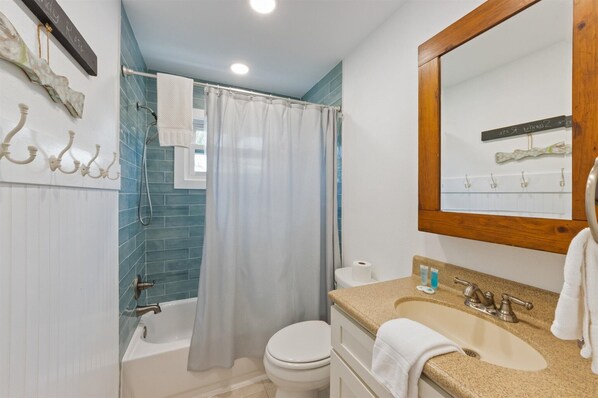 Une salle de bain avec une baignoire, des toilettes, un lavabo et un miroir.