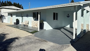A modern house with a covered porch, stone wall, and a small garden area.