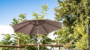 Een terras met twee lounge fauteuils en een grote parasol.