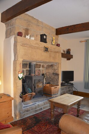 A cozy living room with a stone fireplace, a television, and a wooden table. - 2 Bed Cottage - Sleeps 4 - Pets - Parking (Hebden Bridge)