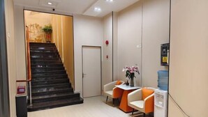 A reception area with a staircase, a reception desk, two chairs, a water dispenser, and a door. - YuanRui Hotel ( Financial City Keyun Road Subway Station Store) (Guangzhou)