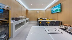A modern conference room with a white table, chairs, a TV, and a kitchen area with appliances. - YuanRui Hotel ( Financial City Keyun Road Subway Station Store) (Guangzhou)