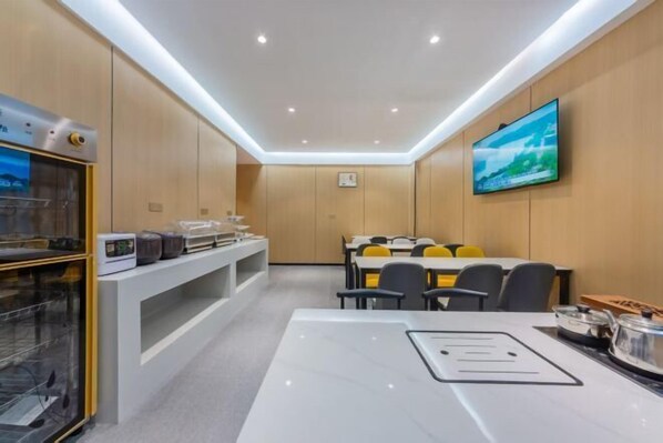 A modern conference room with a white table, chairs, a TV, and a kitchen area with appliances. - YuanRui Hotel ( Financial City Keyun Road Subway Station Store) (Guangzhou)