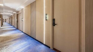 A hotel corridor with a long hallway, wooden doors, and a carpeted floor. - YuanRui Hotel ( Financial City Keyun Road Subway Station Store) (Guangzhou)