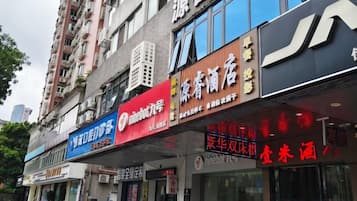 A row of commercial buildings with various storefronts, including a pharmacy and a store with a red sign.