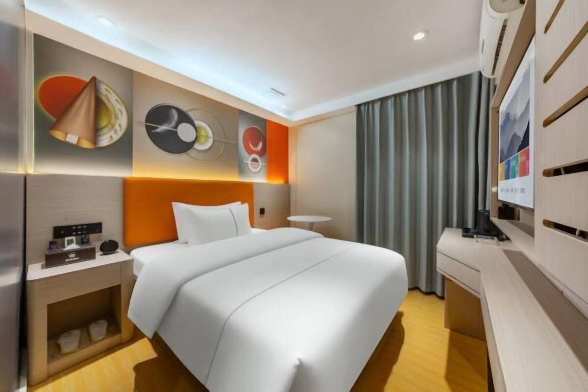 A modern hotel room with a large bed, a desk, and a television.