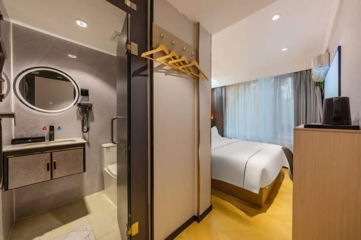 A hotel room with a bed, a bathroom with a mirror, a toilet, and a wardrobe.