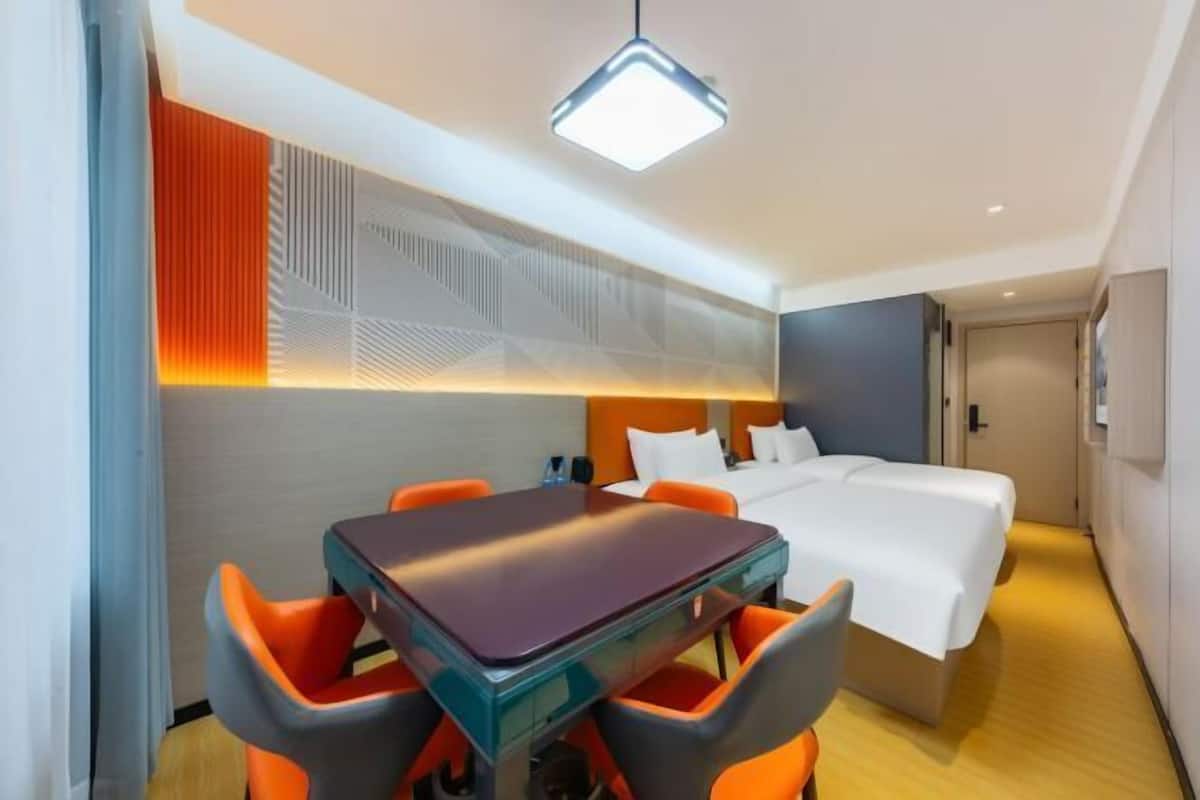 A hotel room with a bed, a table with chairs, and a ceiling light.